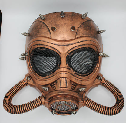 A steampunk-style copper-colored gas mask with black mesh eye panels, metal spikes, and corrugated breathing tubes.
